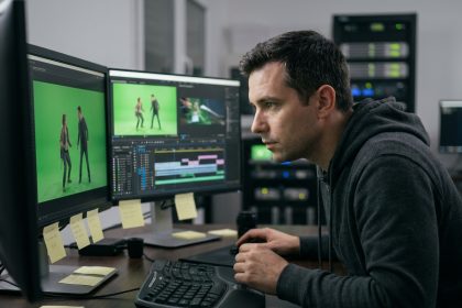 Artiste VFX masculin travaillant sur des logiciels de compositing dans un studio de post-production professionnel avec plusieurs écrans